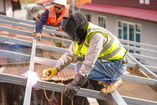 Skilled construction workers perform welding tasks on metal framework at a construction site, showcasing teamwork and safety measures in action.