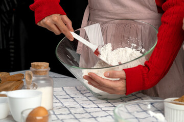 Close-up of hands mixing flour in a glass bowl with spatula, holiday baking preparation scene, cozy kitchen moment, cookie dough setup