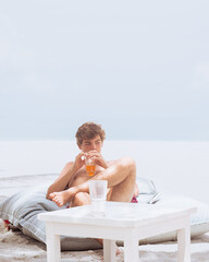 Young man relaxing drinking beverage on beach vacation
