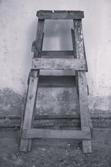 Rustic Wooden Sawhorse Against a Textured Wall in Black and White.
