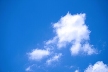 A single fluffy white cumulus cloud in a vast clear blue sky.