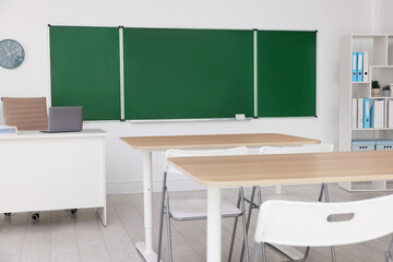 Green chalkboard, desks and chairs in classroom. Mockup for design
