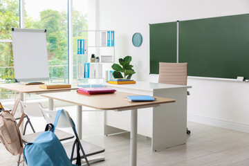 Green chalkboard and stylish furniture in classroom. Mockup for design
