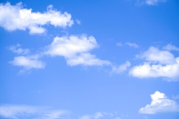 Bright blue sky with fluffy white cumulus clouds on a sunny day.