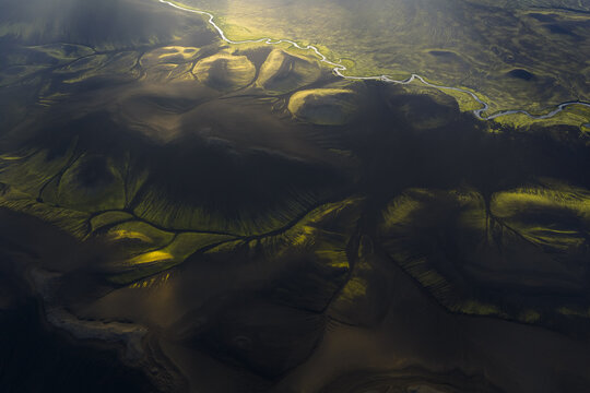 Aerial view of dark, silty waters carve channels through the green and brown landscape, creating a tapestry of contrasting light and shadow, Highlands Of Iceland, Sveitarf&eacute;lagio Hornafjorour, Iceland.