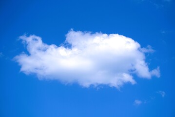 A Single Fluffy White Cloud Drifting in a Clear Blue Sky.
