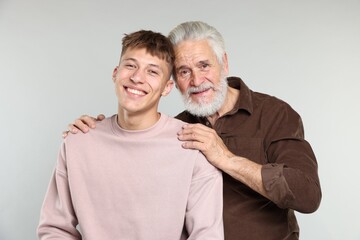 Father hugging his son on light grey background