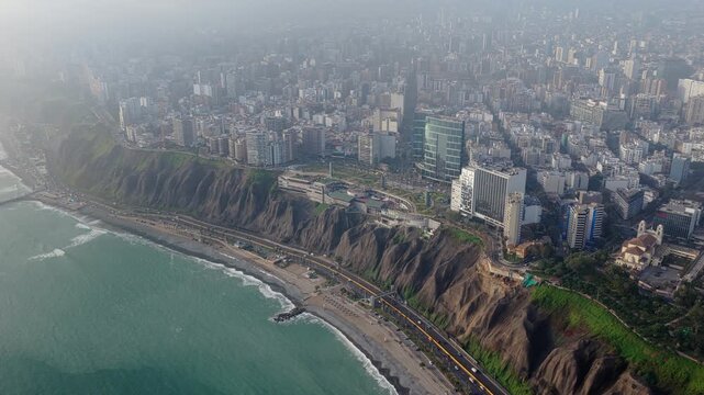 Aerial view of Miraflores district in Lima, Peru, with Costa Verde cliffs on Pacific Ocean coastline, and urban skyline background