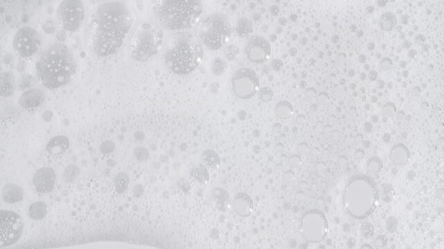 Bubbles of white soap foam. Moving Soap foam popping bubble on a white backdrop. Soap sud macro structure. Clean, cleaning concept, laundry, shower. . High quality 4k footage