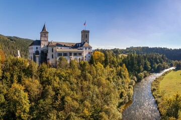 Naklejka premium view of the hilltop Rozmberk Castle surrounded by forest in autumn colour foliage