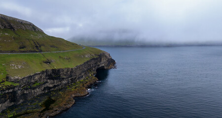 panorama view of the rugged coastline of Sandoy Island and the Husavikervegur Highway in the Faroe...