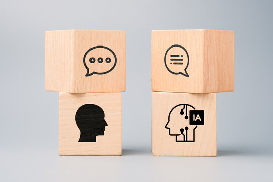 Wooden blocks showing human and AI heads with speech bubbles representing interaction between artificial intelligence and people in modern communication and technology
