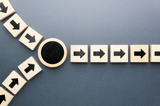 Wooden blocks with arrows merging into a single direction through a black circle, symbolizing unification of ideas, decision alignment, workflow optimization, and integration of multiple processes