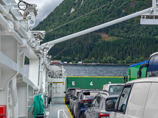 Cars are transported by ferry across a picturesque fjord