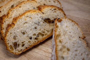 Close-up of fresh, crusty artisan bread slices on a wooden board. The image highlights the bread's airy, porous texture and golden-brown crust. Perfect for food concepts.