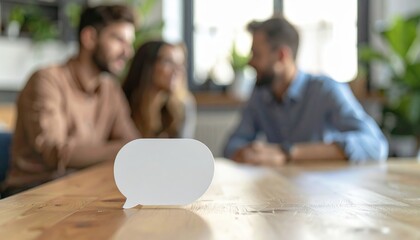 Fototapeta premium Blank Speech Bubble on Wooden Table with Team in Background — Collaboration, Messaging and Customer Feedback Concept