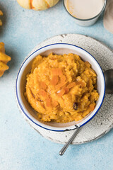 Pumpkin squash porridge with dried apricots and raisins on blue background with pumpkins