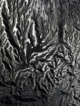 Aerial view of the intricate, textured landscape reveals a tapestry of dark and light patterns, etched by nature's hand, Mount Bromo, East Java, Indonesia.
