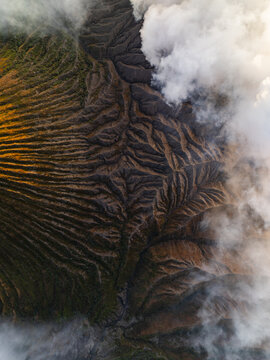 Aerial view of volcanic terrain and wispy clouds create a mesmerizing contrast of textures and tones, Mount Bromo, East Java, Indonesia.