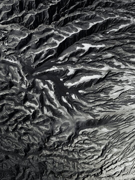 Aerial view of a stark, monochrome landscape revealing the textured, volcanic slopes of Mount Bromo, East Java, Indonesia.