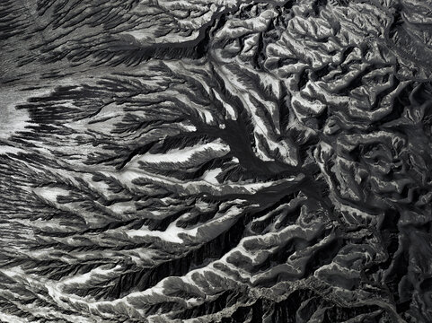 Aerial view of a desolate, monochrome landscape carved by ancient rivers and wind, showcasing nature's raw artistry, Mount Bromo, East Java, Indonesia.