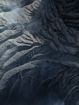 Aerial view of the rugged terrain, unveiling the raw beauty of nature's artistry with its contrasting shadows and textures, Mount Bromo, East Java, Indonesia.