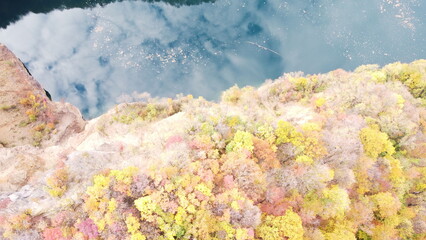 Aerial view of quarry lake with rocky cliffs and sky reflection on calm water