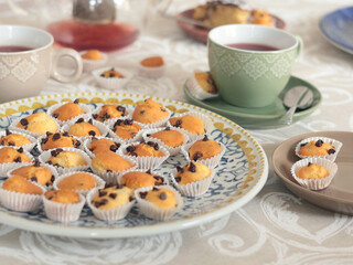 Mini chocolate cupcakes on patterned ceramic plate. Holidays and lifestyle. Food on table covered with tablecloth. 
