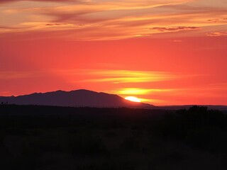 Fototapeta premium Distant mountain range silhouetted against a fiery sunset over the African bushveld, horizon, remote