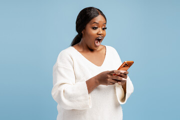 Black woman expressing surprise looking at smartphone screen