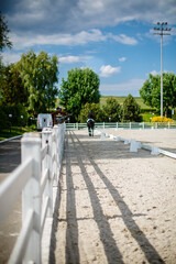 Horse rider training in white paddock equestrian arena landscape on a beautiful day