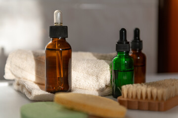 Cosmetic dropper bottles in bathroom with towel on sun rays in bathroom, view from above. Beauty care for face and body care