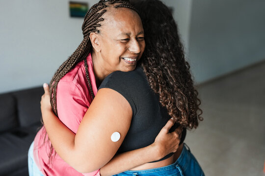 African mother hugging her daughter with diabetes patch - Family lifestyle and people diseases concept - Focus on mother face