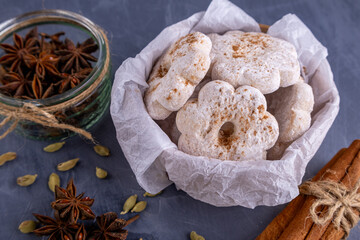 powdered cookie in the shape of a flower with spices on a gray background