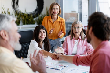 Diverse group of team of professionals working together on project in modern office, shake hands