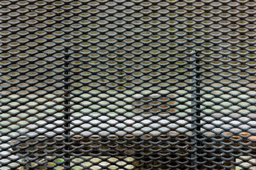 Close-up view of a metal mesh pattern set against an interior wall. The structure shows an interesting design, highlighting the details in the light of day.