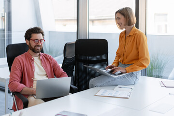 Businessman and businesswoman working in modern office using laptop, copywriter typing on keyboard