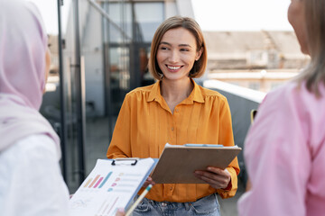 Diverse group of happy multinational woman walking on the street, one female manager wearing hijab
