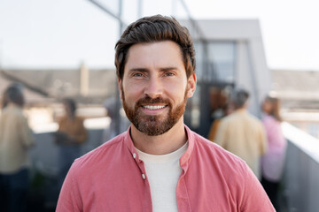 Smiling man wearing casual clothes looking at camera posing on the street. Confident businessman