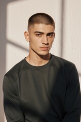 Obraz premium Young man with buzz cut and intense gaze in dark top