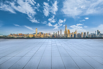 Empty square floor tile plaza providing a panoramic view of the modern city skyline on a clear sunny day.