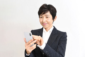 スーツ姿のアジア人シニア女性がスマホ操作