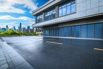Empty parking lot of a modern building with city financial district skyline background.