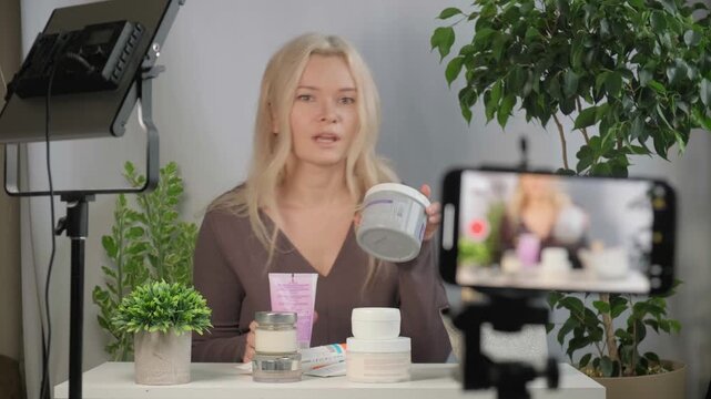 Beauty vlogger or influencer face with girl giving skincare tips or spraying product, creating content for cosmetics promotion or live stream. Woman holding item for makeup or tutorial recording