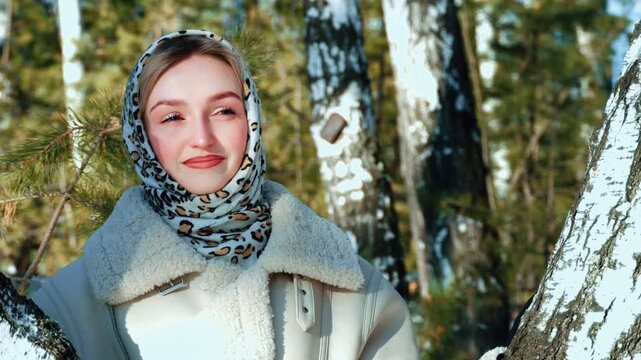A beautiful young girl romantically admires the winter forest and finds peace. Winter walk in nature. Healthy lifestyle.