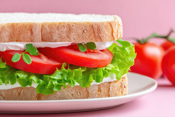 Fresh sandwich with lettuce, tomato, and creamy spread on white bread, close up on plate with pink background, healthy vegan meal, vibrant and appetizing presentation