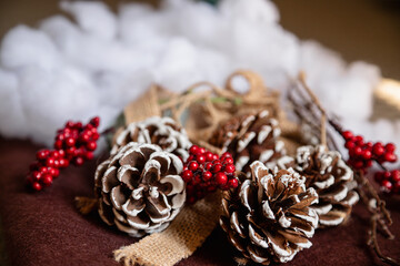 Winter holiday composition with pinecones, snow effect, and red berries. Christmas-inspired decoration offers festive atmosphere, seasonal warmth, and elegant copy space for background or greeting.