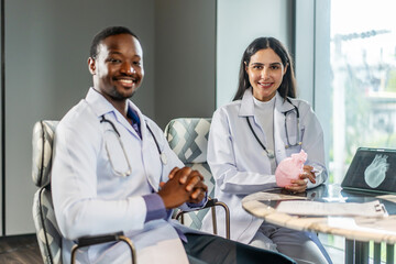 Portrait of a two multi ethnic male and female doctor looking into the camera, wearing white coats sitting in an office hospital, Healthcare and medical service, success and science.