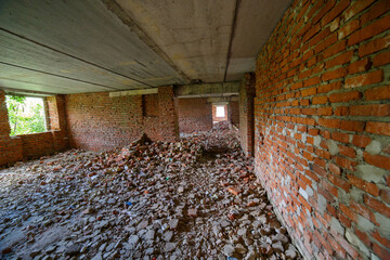 Desolate indoor setting features an abandoned unfinished building filled with debris and bricks...