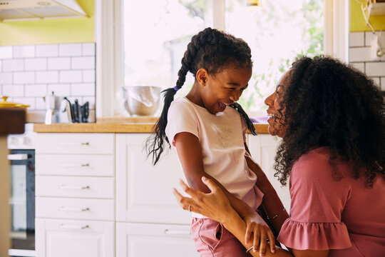Cheerful girl enjoying leisure time with mother at home